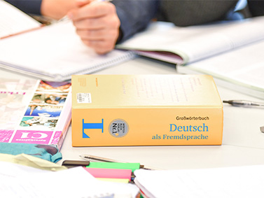 Lernbücher und Deutsch Wörterbuch auf einem Tisch verstreut